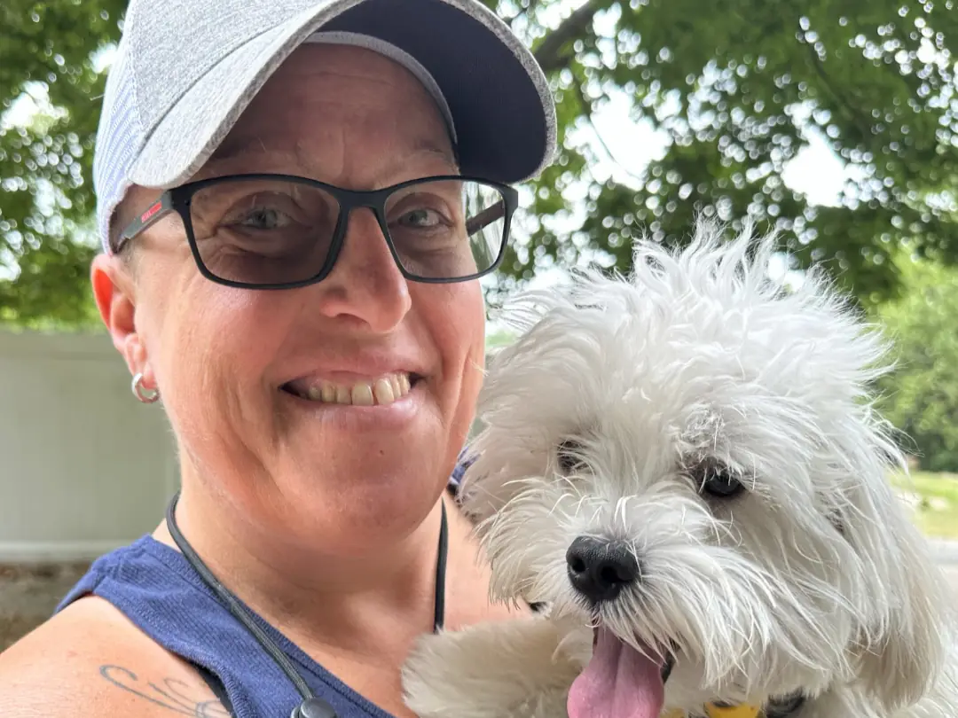 Rikki Fontana, owner of Ruff Haus K9, smiling with a fluffy white dog